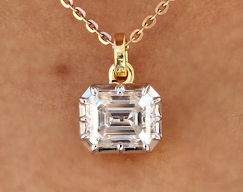 May include: A gold necklace with a large, emerald-cut diamond pendant. The diamond is clear and has a rectangular shape with cut corners. The pendant is set in a gold bezel and hangs from a delicate gold chain.
