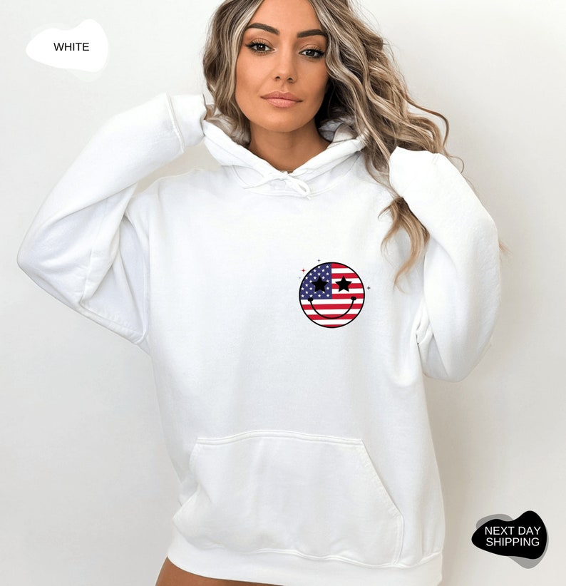 May include: White hooded sweatshirt with a smiley face design featuring the American flag. The smiley face has stars for eyes.