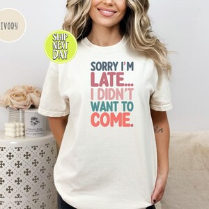 May include: A white t-shirt with the text "Sorry I'm Late... I Didn't Want To Come." in colorful letters.