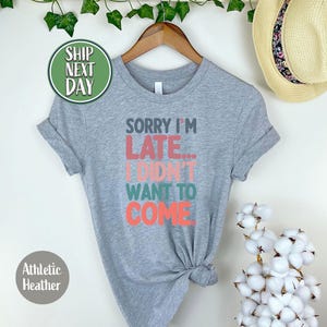 May include: Gray t-shirt with the text "Sorry I'm Late... I Didn't Want To Come" in colorful letters.