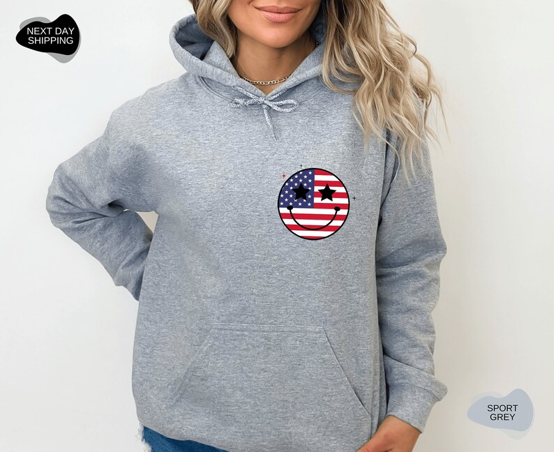 May include: A gray hooded sweatshirt with a smiley face design featuring the American flag. The smiley face has stars for eyes.