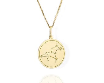 May include: A gold necklace with a round pendant featuring the Virgo constellation. The pendant is engraved with a delicate outline of the constellation.