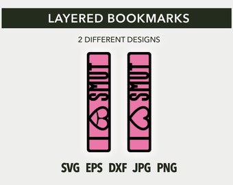 May include: Two pink layered bookmarks with the word "SMUT" in black outlined letters and a black outlined heart. The bookmarks are designed for use with books.