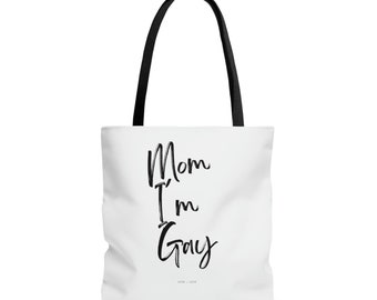May include: White tote bag with black handles and the text "Mom I'm Gay" printed in black.