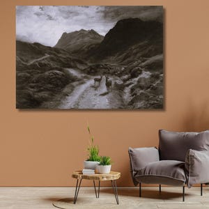 May include: Monochrome landscape painting depicting a mountain range and a dirt track. Two deer stand on the track, with a cloudy sky above. The artwork is displayed above a grey armchair and a small wooden table.