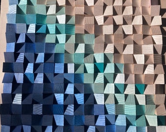 May include: A wall art piece made of wood with a gradient of blue, green, and beige colors. The wood is arranged in a geometric pattern, creating a textured and modern look.
