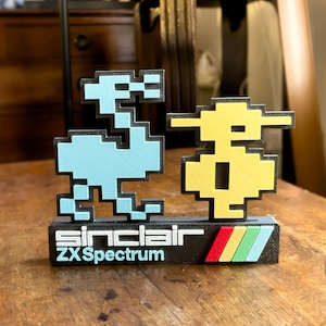 Könnte beinhalten: Ein 3D-gedrucktes Modell des klassischen Videospielcharakters 'Jet Set Willy' vom Sinclair ZX Spectrum. Das Modell ist blau und gelb und trägt den Text 'Sinclair ZX Spectrum' auf einem schwarzen Sockel.