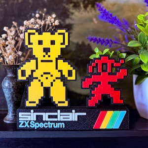 Peut inclure: Une tasse en céramique blanche avec une anse noire et le texte "But First, Coffee" en gras noir. La tasse est posée sur un fond neutre, soulignant son design simple.