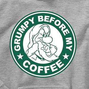 May include: A gray hoodie with a green circle graphic featuring a cartoon character of Grumpy from Snow White and the Seven Dwarfs. The text inside the circle reads "Grumpy Before My Coffee".