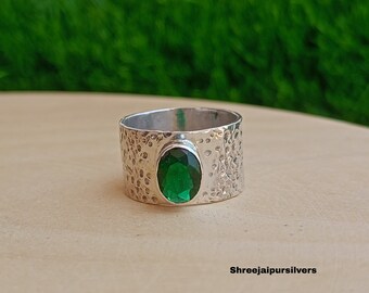 Puede incluir: Un anillo de plata con una banda texturizada y una piedra preciosa ovalada verde.