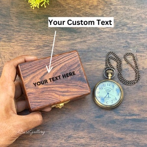 May include: A wooden box with a hinged lid and a brass latch. The box is engraved with the text "YOUR TEXT HERE". A vintage pocket watch with a chain is also pictured.