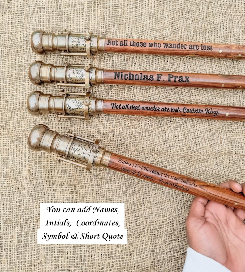 May include: Four wooden walking sticks with brass-colored metal detailing. Each stick has a unique engraved quote or name. One stick reads "Not all those who wander are lost." Another says "Nicholas F. Prax." The image also includes text: "You can add Names, Intials, Coordinates, Symbol & Short Quote."
