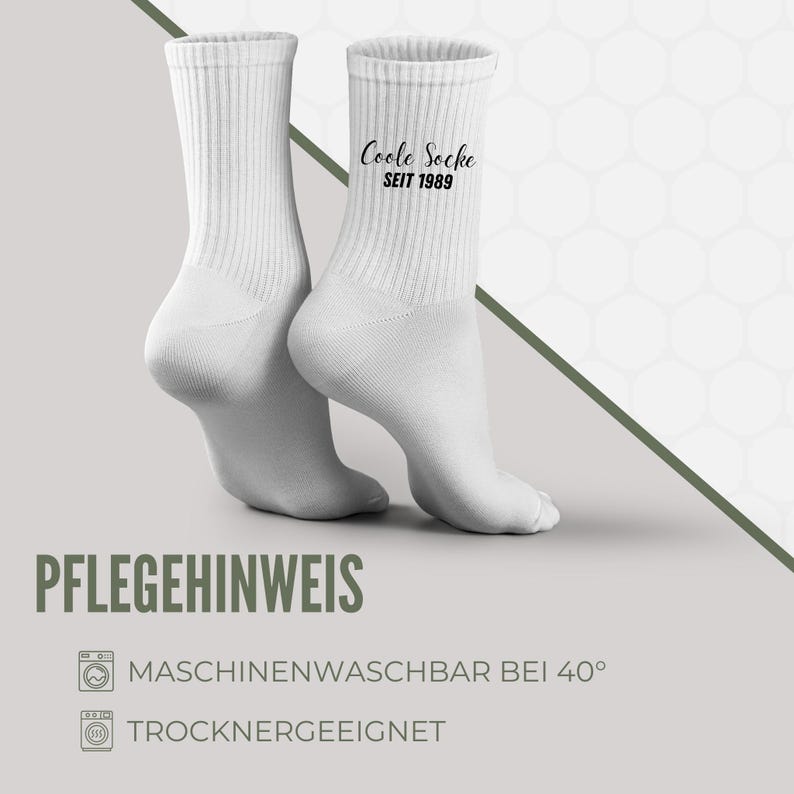 May include: Two white ribbed crew socks. One sock has the text "Coole Socke SEIT 1989" printed in black. The socks are displayed on a light gray background. The image also includes care instructions.