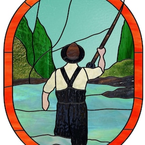 May include: Stained glass artwork depicting a fisherman fly fishing in a river. The artwork features a man in waders and a hat, holding a fishing rod. The background includes green mountains and a blue sky, framed by an orange border.