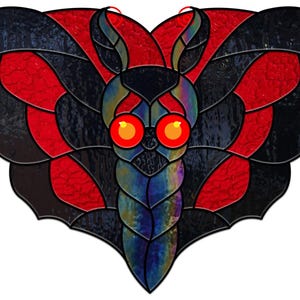 Puede incluir: Una mariposa de vitral con alas negras y rojas y detalles iridiscentes azules y morados. La mariposa tiene ojos grandes, redondos y rojos.