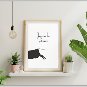 May include: A framed art print with a minimalist design. The print features a black silhouette of a bull and the text "Ingen ko på isen" in a handwritten font. The artwork is displayed on a white shelf with plants.