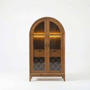 May include: A wooden arched cabinet with glass doors. The cabinet has interior lighting, two drawers, and wine storage. The cabinet is made of light brown wood and has a modern design. The cabinet is on a white background.