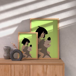 Puede incluir: Dos ilustraciones enmarcadas de un personaje de dibujos animados montando un oso. La ilustraci&oacute;n m&aacute;s grande est&aacute; sobre un fondo verde y la ilustraci&oacute;n m&aacute;s peque&ntilde;a est&aacute; sobre un fondo blanco. Las ilustraciones est&aacute;n en un estante de madera con un jarr&oacute;n y un objeto decorativo.