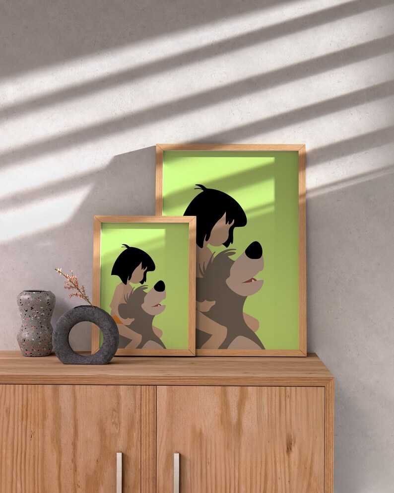 Puede incluir: Dos ilustraciones enmarcadas de un personaje de dibujos animados montando un oso. La ilustraci&oacute;n m&aacute;s grande est&aacute; sobre un fondo verde y la ilustraci&oacute;n m&aacute;s peque&ntilde;a est&aacute; sobre un fondo blanco. Las ilustraciones est&aacute;n en un estante de madera con un jarr&oacute;n y un objeto decorativo.