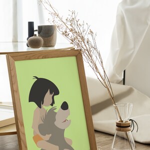 Puede incluir: Una impresi&oacute;n enmarcada de una ilustraci&oacute;n de dibujos animados de Mowgli del Libro de la Selva de Disney montando a Baloo el oso. La impresi&oacute;n est&aacute; sobre un fondo verde claro y est&aacute; enmarcada en un marco de madera marr&oacute;n claro.