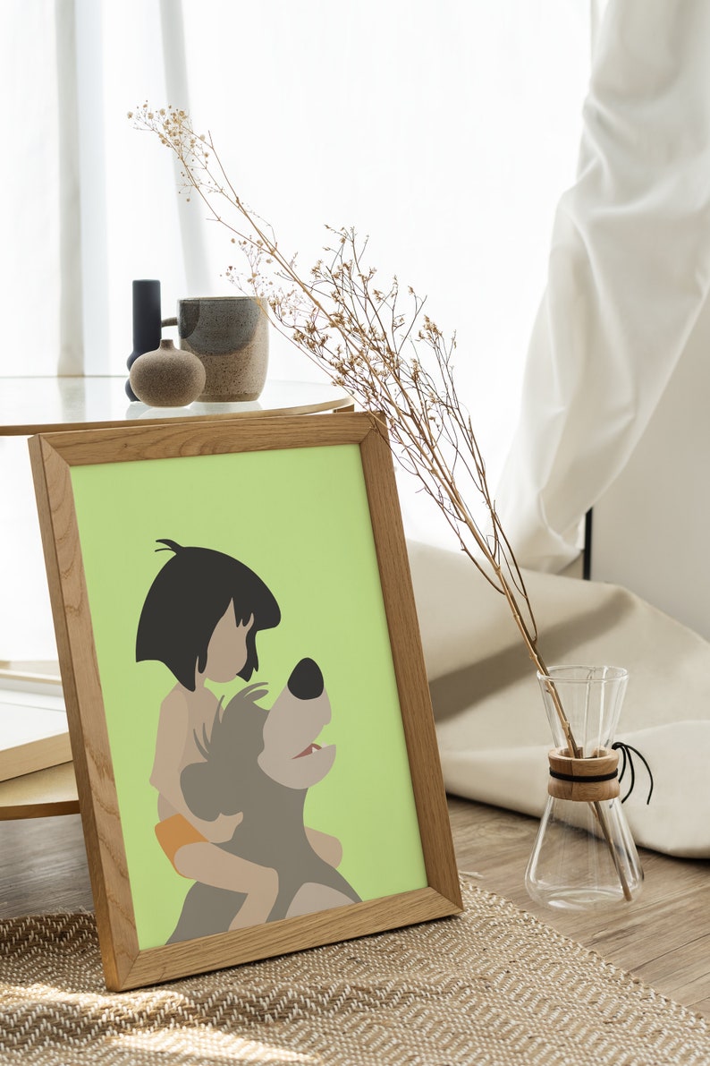 Puede incluir: Una impresi&oacute;n enmarcada de una ilustraci&oacute;n de dibujos animados de Mowgli del Libro de la Selva de Disney montando a Baloo el oso. La impresi&oacute;n est&aacute; sobre un fondo verde claro y est&aacute; enmarcada en un marco de madera marr&oacute;n claro.