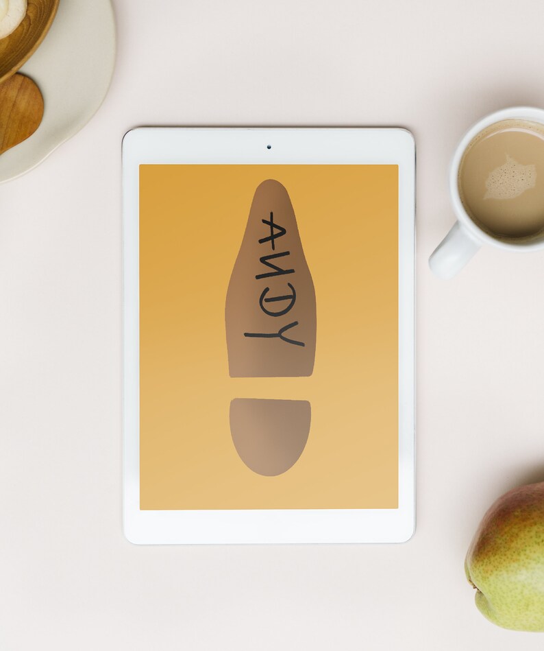 May include: A digital tablet displays a brown footprint graphic with the name "ANDY" in black. The tablet is on a light pink surface, accompanied by a cup of coffee and a pear.
