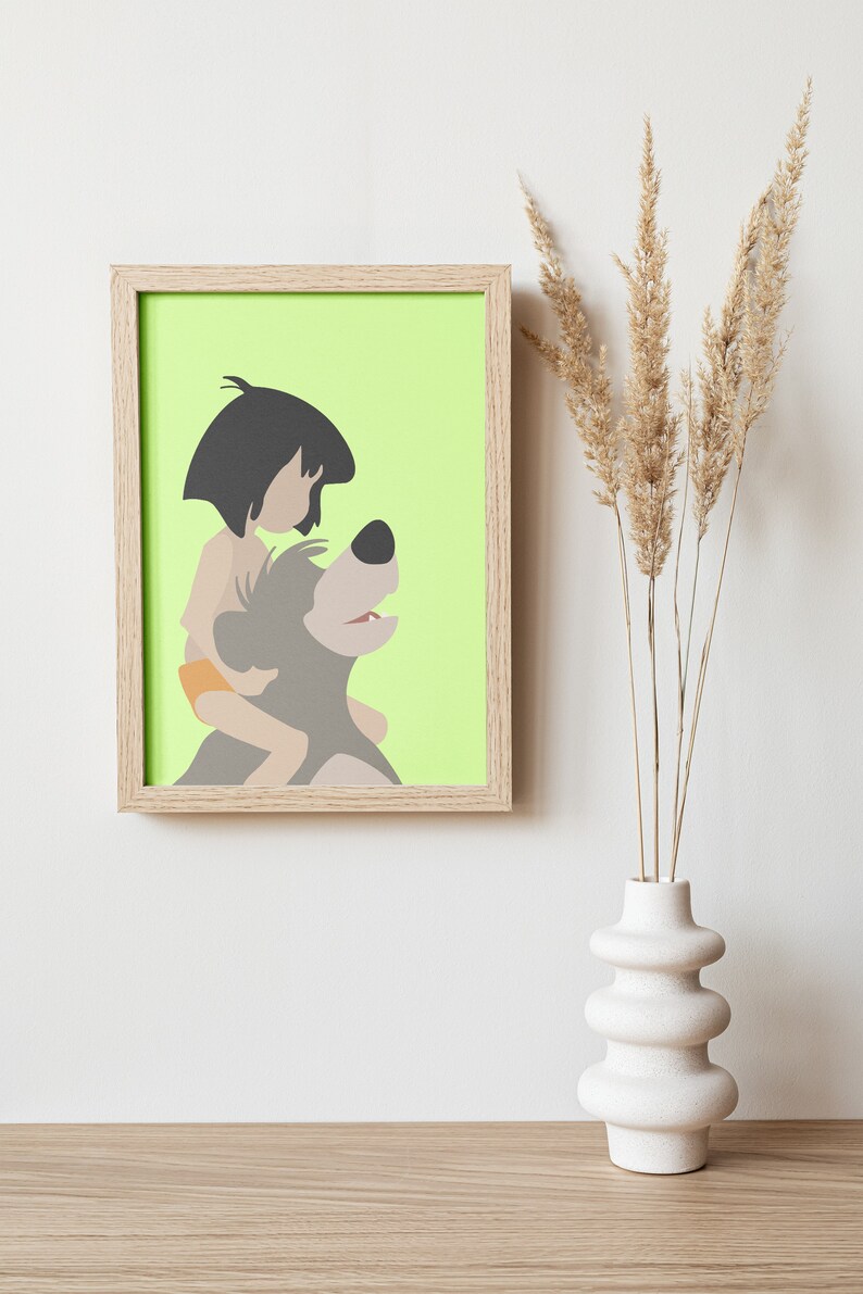 Puede incluir: Una impresi&oacute;n enmarcada de una ilustraci&oacute;n de dibujos animados de un ni&ntilde;o montando un oso. La impresi&oacute;n est&aacute; sobre un fondo verde claro y est&aacute; enmarcada en un marco de madera claro.