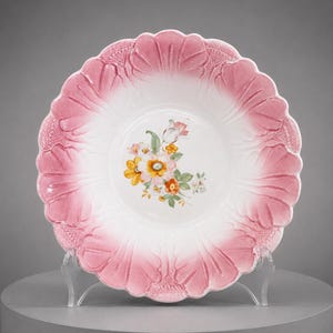 May include: A round ceramic bowl with a scalloped edge featuring a gradient pink finish that transitions to a white center. The center of the bowl is decorated with a colorful floral illustration of yellow, orange, and white flowers with green leaves.