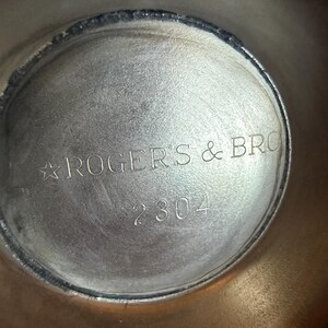 May include: Close-up of the interior of a silver-toned metal object. The text "ROGERS & BRO" is stamped in a curved line, with the number "2304" below. The metal has a slightly textured surface.