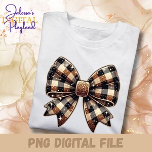 Op de afbeelding: Wit T-shirt met een groot decoratief strikdesign. De strik heeft een ruitpatroon in bruin, zwart en goud, met glitteraccenten. De tekst "PNG DIGITAL FILE" staat onderaan. De tekst "Jalessa's Digital Playland" staat linksboven.