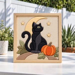May include: A square framed wall art piece featuring a layered felt applique design of a black cat sitting in front of a pale yellow crescent moon and three small stars. An orange pumpkin and green leaves are positioned at the base of the cat.