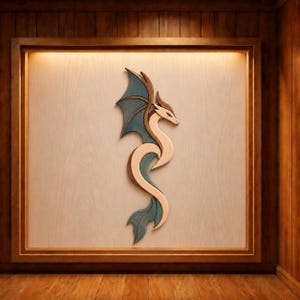 Puede incluir: Arte mural de dragón de madera. El dragón tiene un cuerpo de madera clara con alas y cola de color verde azulado. La obra de arte está enmarcada en un marco de madera y montada sobre un fondo de madera clara.