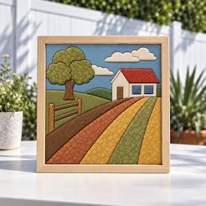 Pode incluir: Uma peça de arte de parede em tecido quadrada numa moldura de madeira clara que retrata uma paisagem rural. A cena apresenta uma casa branca com telhado vermelho, uma grande árvore verde, uma cerca de madeira e filas diagonais de tecido castanho, laranja, amarelo e verde.