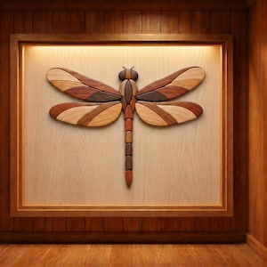 May include: Wooden dragonfly wall art. The dragonfly is crafted from various wood tones, including light and dark browns, and tans. The dragonfly is mounted on a light wood panel, framed in a darker wood, and set against a wood-paneled wall.