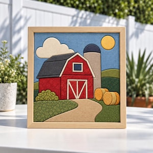 May include: A framed fabric wall art piece depicting a red barn with a dark roof, a gray silo, a yellow sun, and a white cloud against a blue sky. The scene includes green rolling hills, a tan dirt path, and two round hay bales in the foreground.
