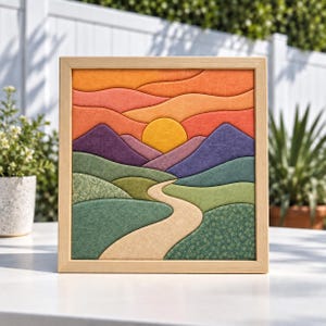 Pode incluir: Uma peça de arte de parede em tecido emoldurada de formato quadrado com uma paisagem em camadas. O design exibe um sol amarelo sobre montanhas roxas, com colinas verdes e um caminho bege sinuoso. Os tecidos incluem cores sólidas e padrões florais.