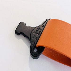 May include: Close-up of a brown leather strap with a black Cobra Pro Style buckle. The buckle has a small arrow pointing to the right and the text "7/8" above the Cobra logo.