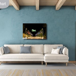 May include: A white couch with blue pillows sits in a living room with a blue wall and a wooden door. A framed photograph of a street lined with colorful flags hangs on the wall above the couch. The image is labeled "Livingroom size chart" and "24x36 in".