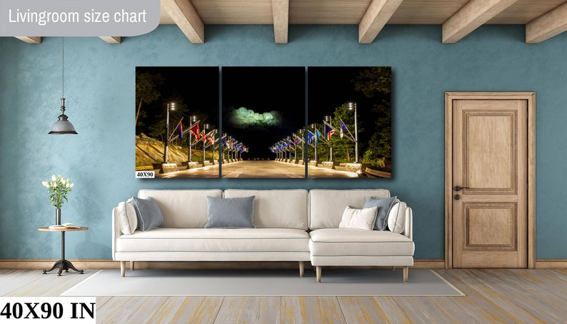 May include: A three-panel canvas print of a nighttime street scene with flags and streetlights. The print is 40 inches wide by 90 inches tall and is displayed on a white couch in a living room.