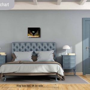 May include: A bedroom with a king-size bed, two nightstands with lamps, and a framed picture on the wall. The bed is made with white bedding and has a blue headboard. The nightstands are blue and have three drawers each. The picture is a landscape scene with a green and yellow color scheme. The room is painted a light blue color. The text "Bedroom size chart" is at the top of the image. The text "King Size Bed, 6ft 3in wide" is at the bottom of the image. The text "16x20 IN" is in the bottom left corner of the image.