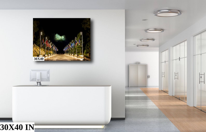 May include: A night time photo of a street lined with lampposts and flags. The flags are a variety of colors and designs. The street is empty and the lights are on. The image is 30x40 inches.