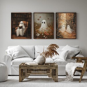 May include: Three framed paintings of ghosts in different settings. The first painting shows a ghost reading a book in a library. The second painting shows a ghost in a field of flowers. The third painting shows two ghosts walking in a forest.