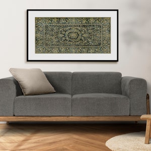 K&ouml;nnte beinhalten: Ein graues Stoff-Sofa mit einem Holzrahmen und einem beigefarbenen Kissen. &Uuml;ber dem Sofa h&auml;ngt ein gerahmtes Bild eines blauen und goldenen gemusterten Teppichs.