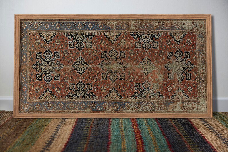 K&ouml;nnte beinhalten: Ein gerahmter Vintage-Teppich mit einem geometrischen Muster in Rot, Blau und Schwarz. Der Teppich befindet sich in einem Holzrahmen und h&auml;ngt an einer wei&szlig;en Wand.
