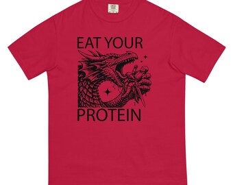 May include: A red t-shirt with a black graphic of a dragon holding a knife, with the words "EAT YOUR PROTEIN" printed above and below the dragon illustration. The shirt has short sleeves and a crew neck.
