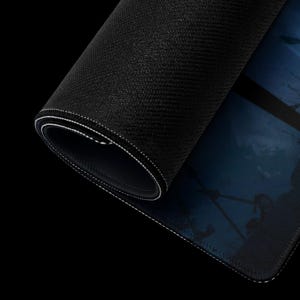 May include: A black gaming mouse pad with a blue and white design. The mouse pad is rolled up and the edge is visible.
