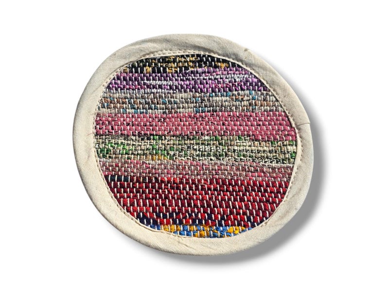 May include: Round woven rug with a white border and a colorful striped pattern in shades of pink, red, green, blue, and purple.