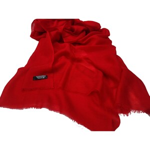Puede incluir: Un chal de pashmina rojo brillante con un borde de flecos. El chal está hecho de una tela suave y lujosa y es perfecto para agregar un toque de elegancia a cualquier atuendo.