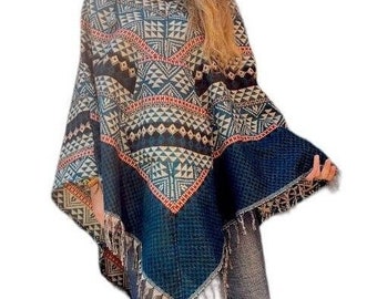 May include: A poncho featuring a dark blue base with a multi-colored geometric pattern in shades of orange, white, and black. The garment has a high turtleneck collar, a pointed hemline, and a fringe trim along the bottom edge of the fabric.