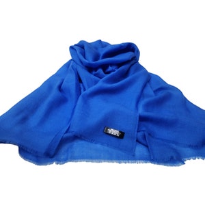 Puede incluir: Un chal de pashmina azul brillante con un borde con flecos. El chal está hecho de 100% cachemira y es suave y lujoso.